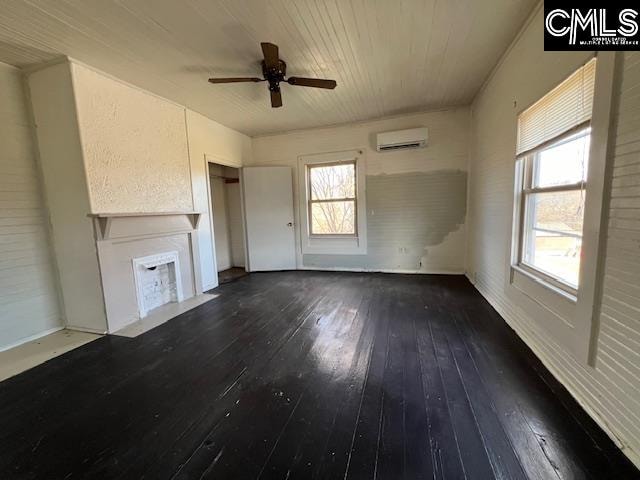 unfurnished living room featuring a wall unit AC, hardwood / wood-style floors, a wealth of natural light, and ceiling fan