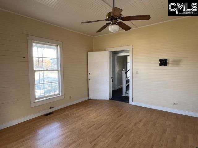 spare room with plenty of natural light, ceiling fan, and wood-type flooring