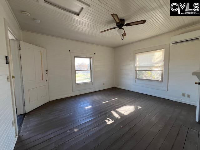 spare room with a wall mounted air conditioner, ceiling fan, and dark wood-type flooring