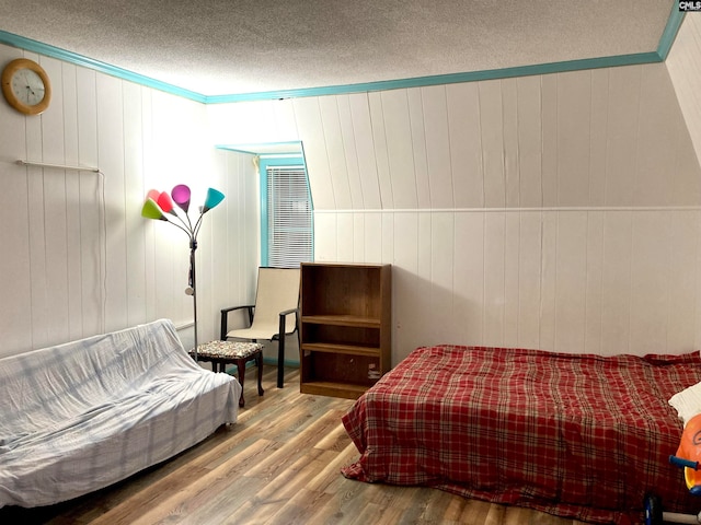 bedroom featuring ornamental molding, light wood-type flooring, and a textured ceiling