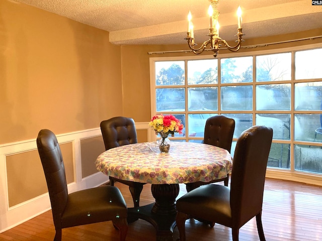 dining room with a notable chandelier, a textured ceiling, and hardwood / wood-style floors