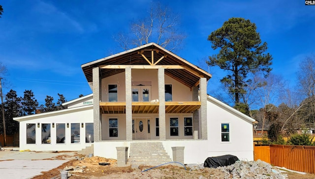 exterior space with a sunroom, fence, a balcony, and stucco siding