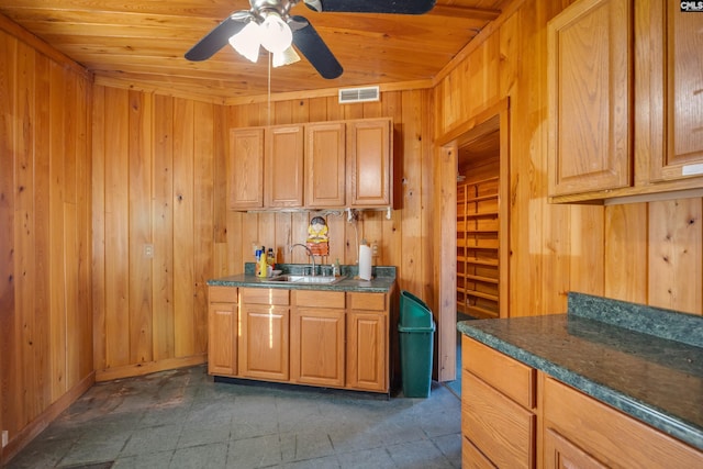 kitchen with ceiling fan, wood ceiling, wooden walls, sink, and dark tile floors