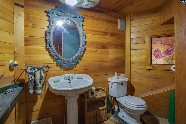 bathroom with wood ceiling, sink, wood walls, and toilet