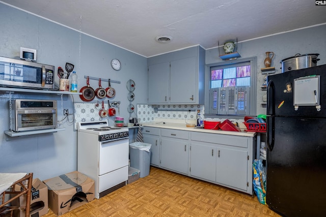 kitchen featuring white gas range, blue cabinetry, backsplash, black refrigerator, and light parquet flooring