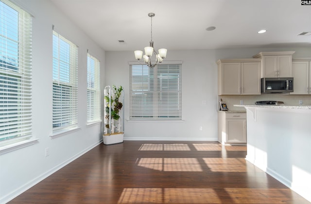 kitchen featuring dark hardwood / wood-style flooring, a notable chandelier, decorative light fixtures, and light stone countertops