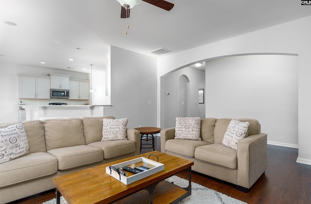 living room with ceiling fan and dark hardwood / wood-style flooring