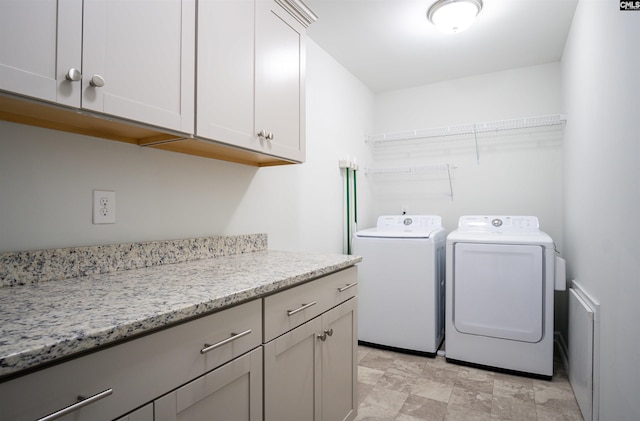 laundry area featuring cabinets, washer and dryer, and light tile floors