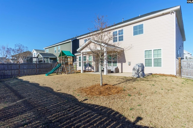 back of property featuring a lawn, a patio area, and a playground