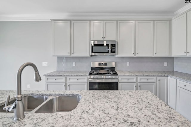 kitchen featuring white cabinetry, sink, light stone counters, backsplash, and appliances with stainless steel finishes