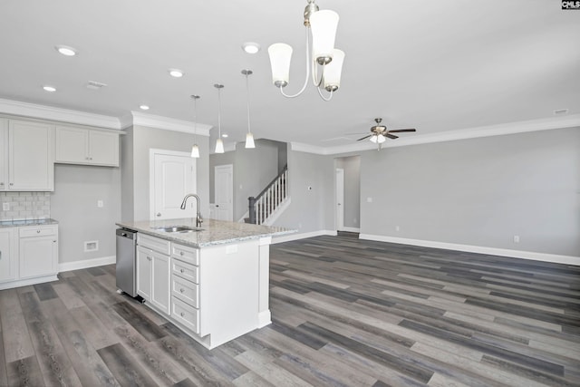 kitchen featuring dishwasher, a center island with sink, sink, hanging light fixtures, and light stone counters