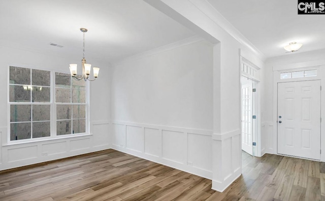 entrance foyer featuring hardwood / wood-style flooring, an inviting chandelier, and ornamental molding