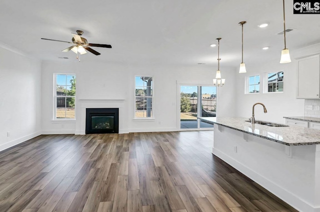 kitchen featuring sink, light stone countertops, decorative light fixtures, a kitchen bar, and white cabinetry