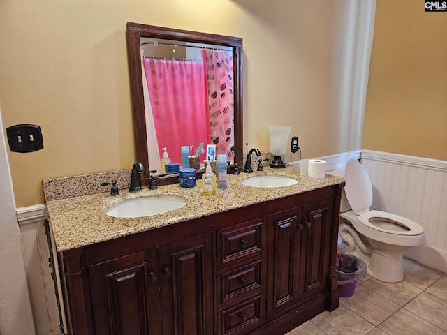 bathroom featuring tile floors, double vanity, and toilet