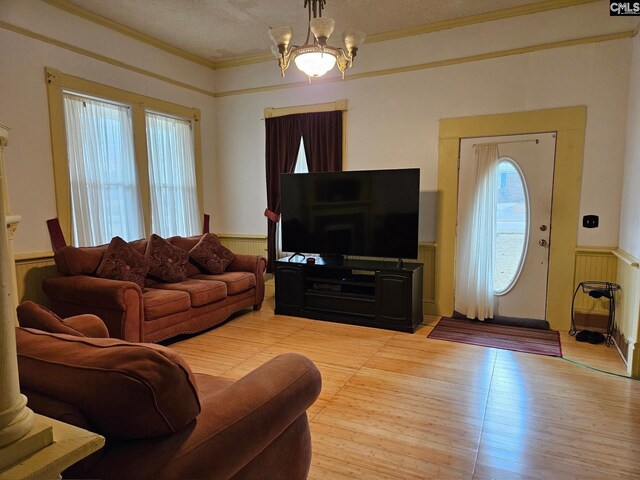 living room with a notable chandelier, a textured ceiling, crown molding, and light hardwood / wood-style floors