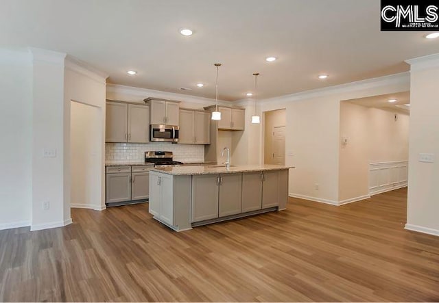 kitchen with gray cabinetry, hanging light fixtures, stainless steel appliances, hardwood / wood-style floors, and a center island with sink