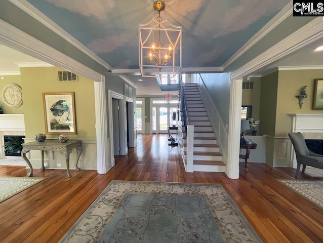 foyer featuring ornamental molding, dark wood-type flooring, and an inviting chandelier