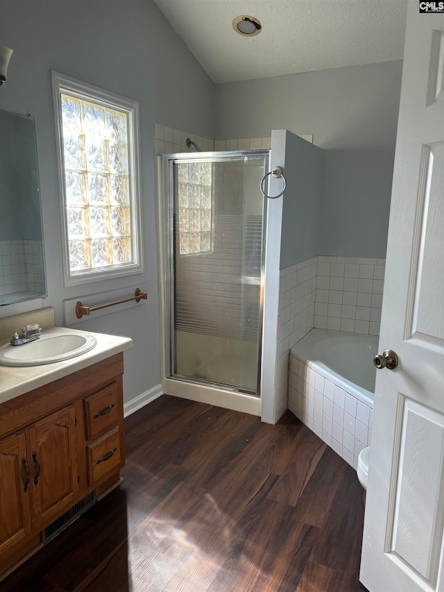 full bathroom featuring vanity, hardwood / wood-style floors, separate shower and tub, a textured ceiling, and lofted ceiling