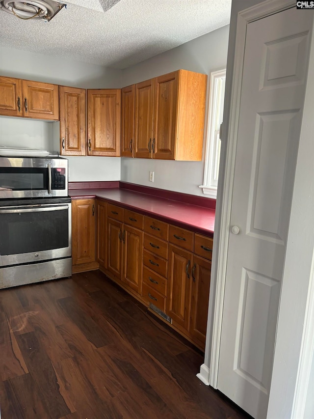 kitchen featuring dark wood-type flooring, wall oven, and a textured ceiling