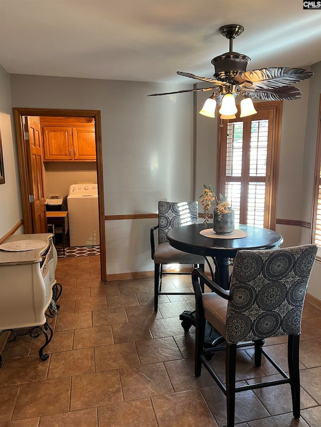 dining space with ceiling fan, washer / dryer, and dark tile flooring