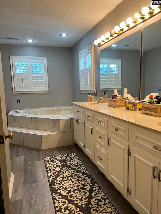 bathroom with tiled tub, vanity, and hardwood / wood-style flooring