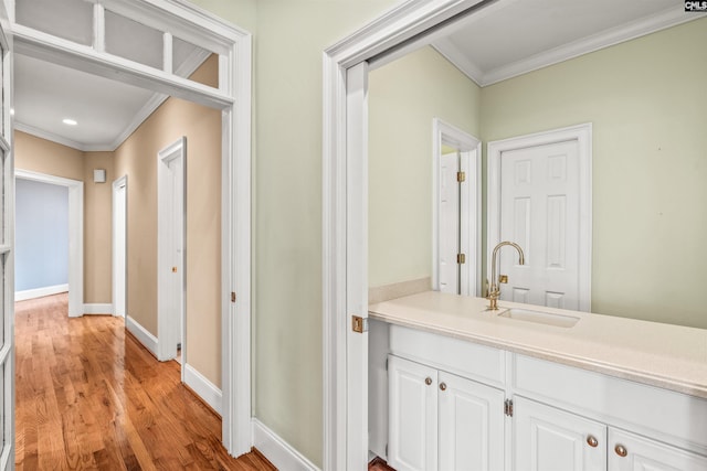 hallway featuring ornamental molding, sink, and light wood-type flooring