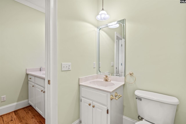 bathroom with toilet, vanity with extensive cabinet space, and hardwood / wood-style flooring