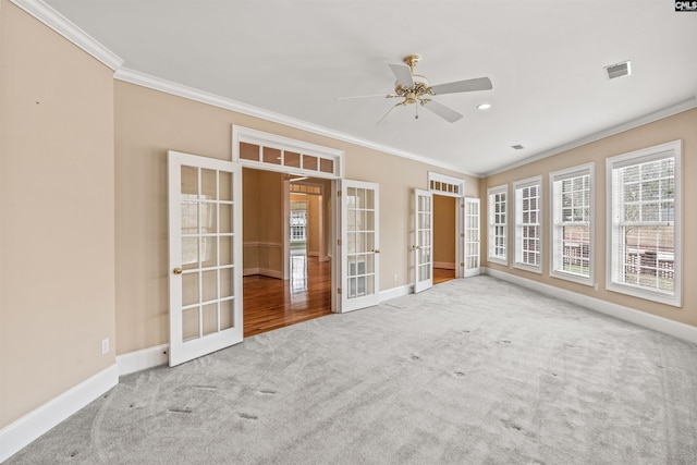 spare room with light carpet, crown molding, and french doors