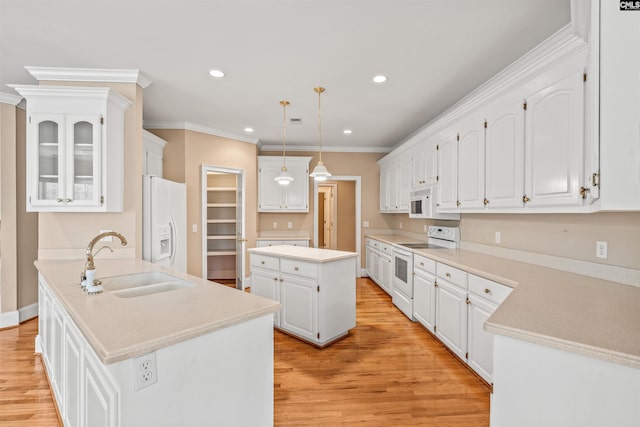 kitchen with a center island with sink, white appliances, white cabinets, light wood-type flooring, and sink