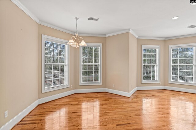 unfurnished room featuring crown molding, an inviting chandelier, and light wood-type flooring