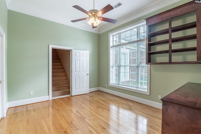 interior space with light hardwood / wood-style floors, ornamental molding, ceiling fan, and multiple windows