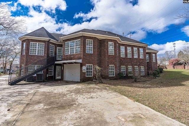 view of front of house with a front lawn, central air condition unit, and a garage