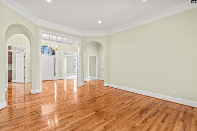 spare room featuring light hardwood / wood-style floors, ornamental molding, and a chandelier