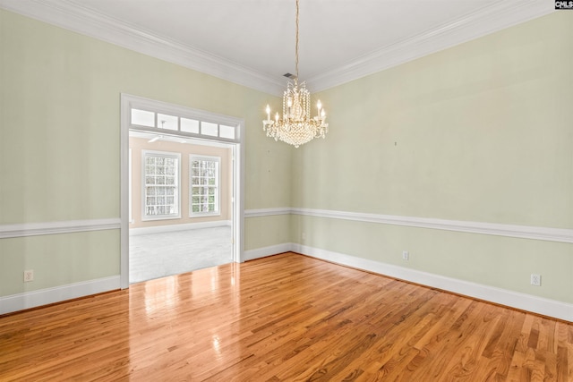 spare room with a chandelier, ornamental molding, and light hardwood / wood-style flooring