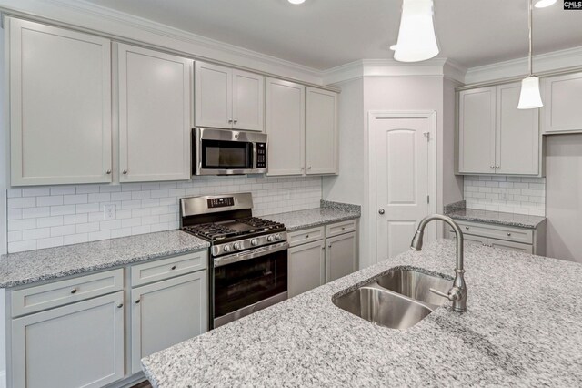 kitchen with pendant lighting, a sink, backsplash, appliances with stainless steel finishes, and crown molding