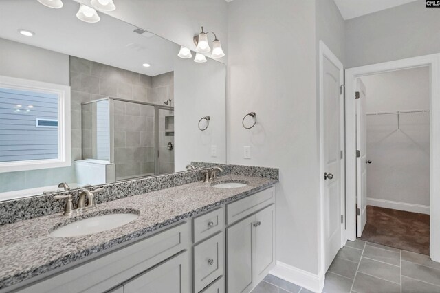 bathroom featuring double vanity, tile patterned flooring, a stall shower, and a sink