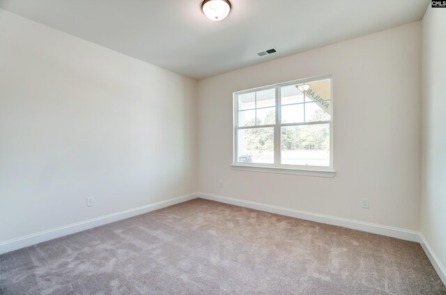 carpeted empty room featuring baseboards and visible vents