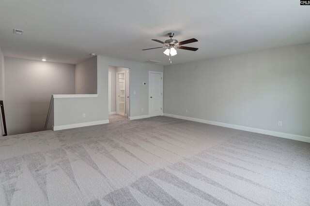 carpeted empty room featuring a ceiling fan, visible vents, and baseboards