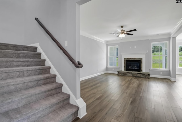 unfurnished living room featuring dark wood-style floors, a fireplace, stairs, and a ceiling fan