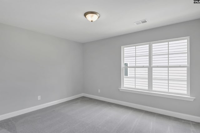 carpeted empty room with a wealth of natural light, visible vents, and baseboards