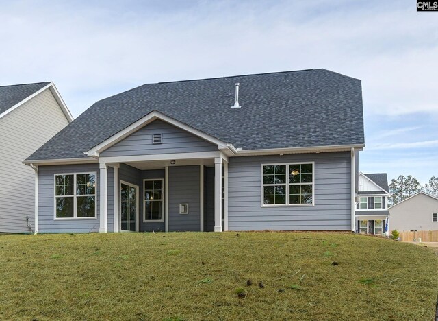 exterior space with a shingled roof and a front lawn