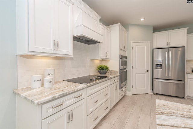 kitchen featuring light stone counters, appliances with stainless steel finishes, custom range hood, and white cabinets