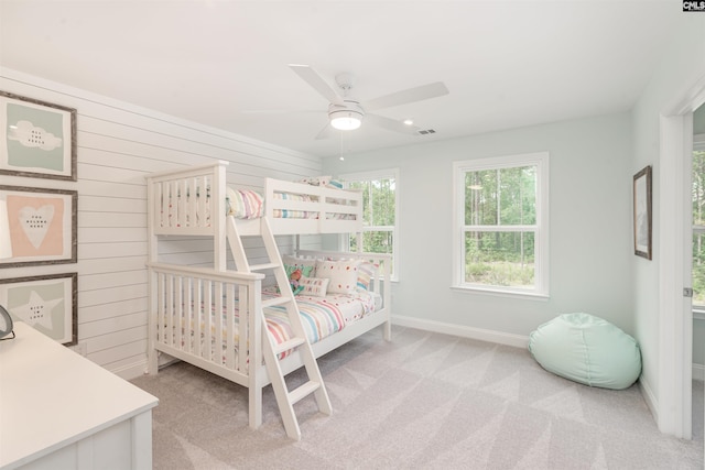 carpeted bedroom featuring ceiling fan and wooden walls