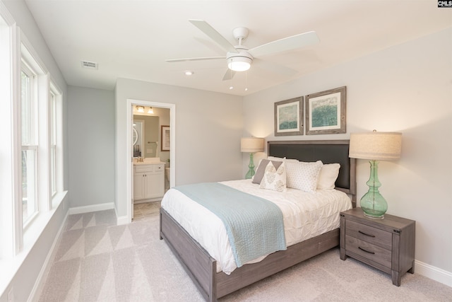 bedroom featuring connected bathroom, light colored carpet, and ceiling fan