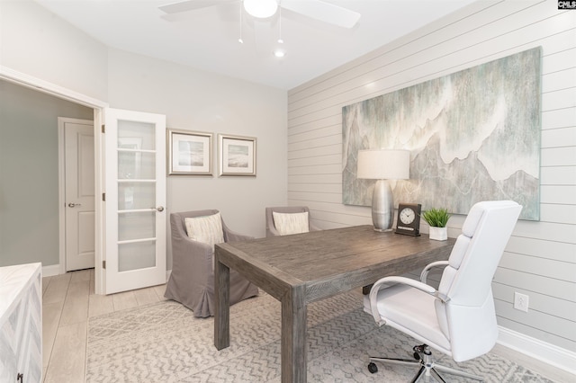 office space with french doors, ceiling fan, and wood walls