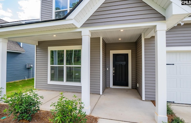 doorway to property with a porch and a garage