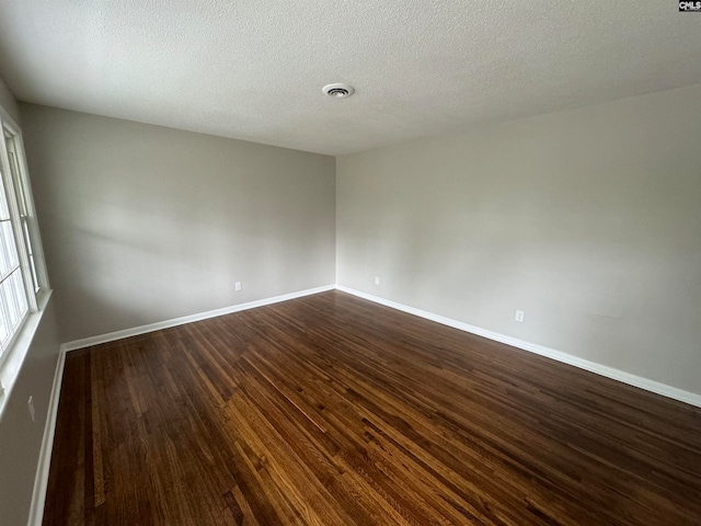 empty room featuring a textured ceiling and dark wood-type flooring