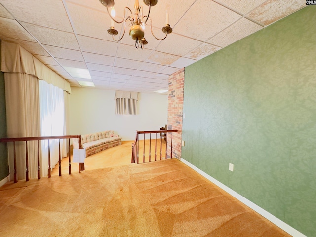 interior space with a drop ceiling, a chandelier, and carpet flooring