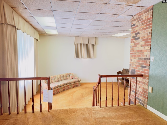 sitting room featuring a drop ceiling and carpet flooring