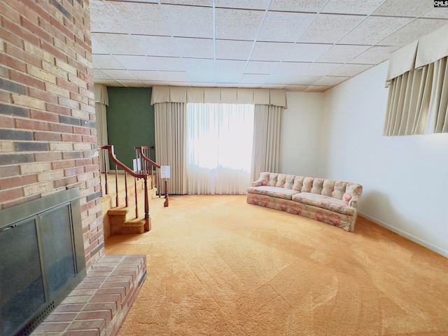 sitting room featuring a paneled ceiling, carpet floors, and a brick fireplace